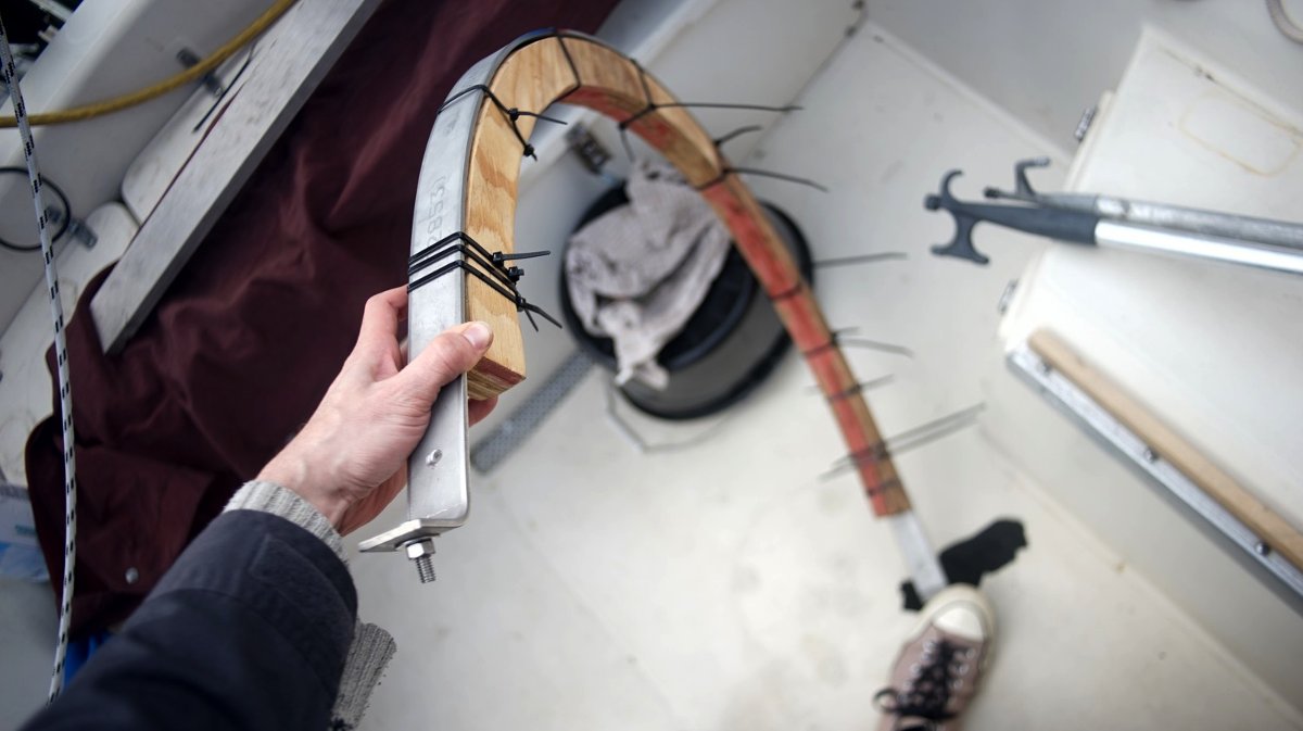 a length of flat metal secured to a wooden arch with a bunch of zip ties