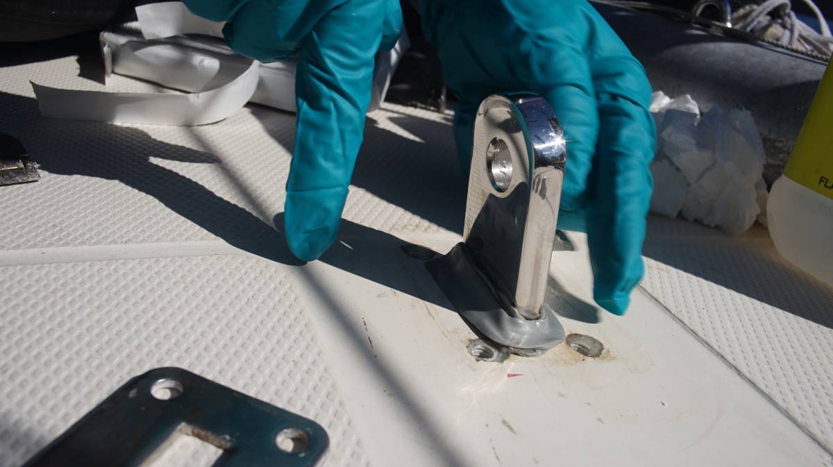 a gloved hand is applying some butyl tape around the chainplate hole at the deck level