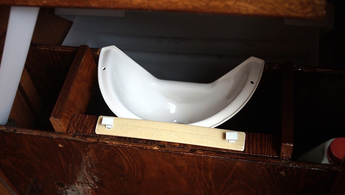 Photo of how we secured the urine diverter down, using an old mainsail batten and plastic screws