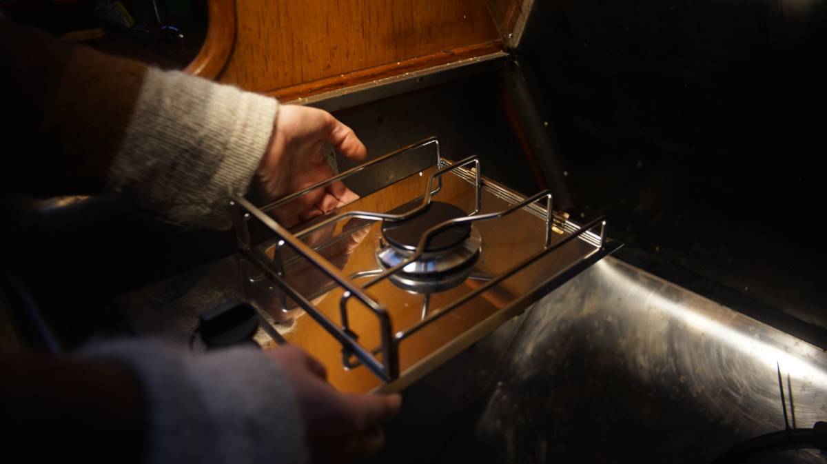 hands holding a single LPG burner over an empty spot in the galley