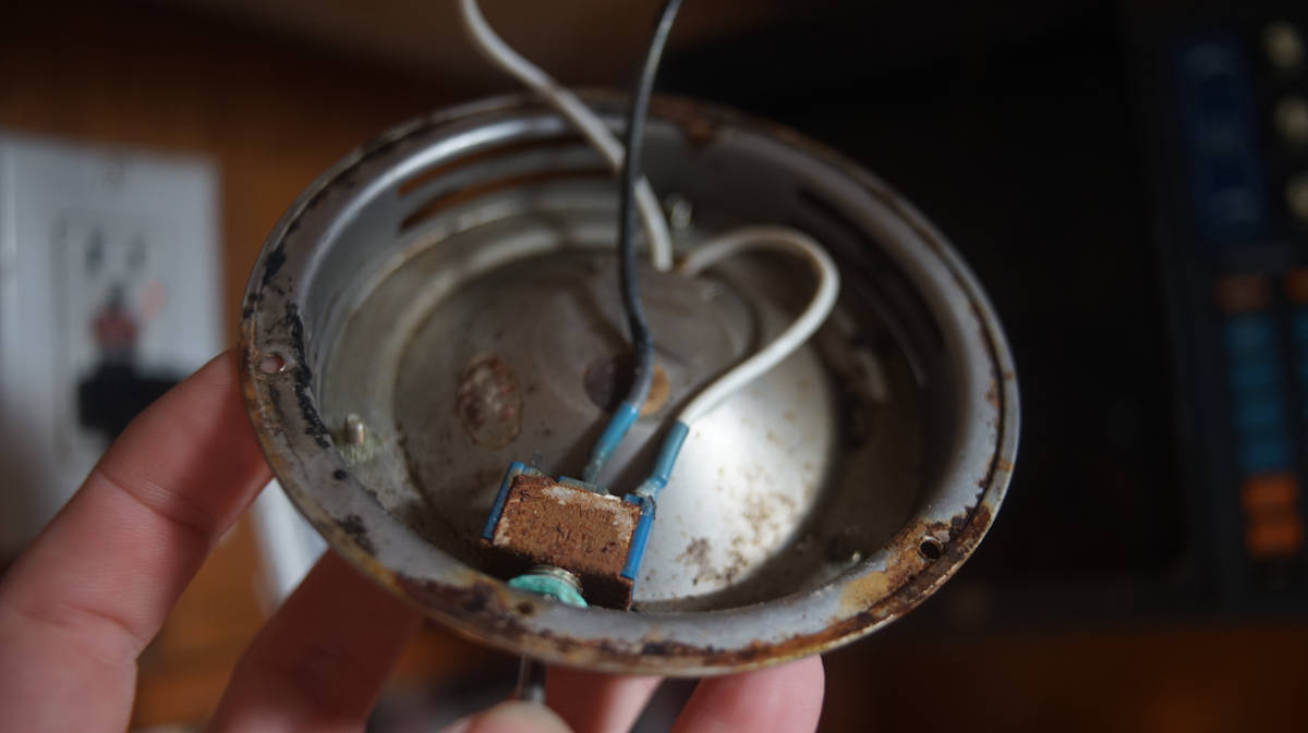 a view of the inside of a dome lamp with the switch and inside showing some rust