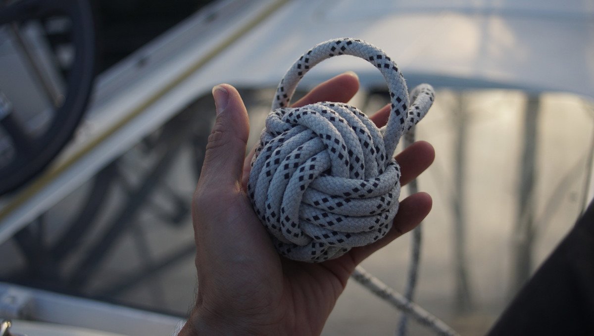 A hand holding a monkey fist made from old rope