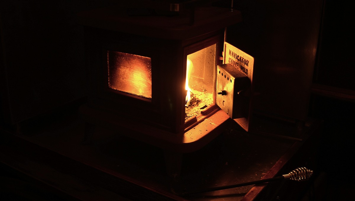 A photo of a sardine woodstove with a small fire roaring inside its belly