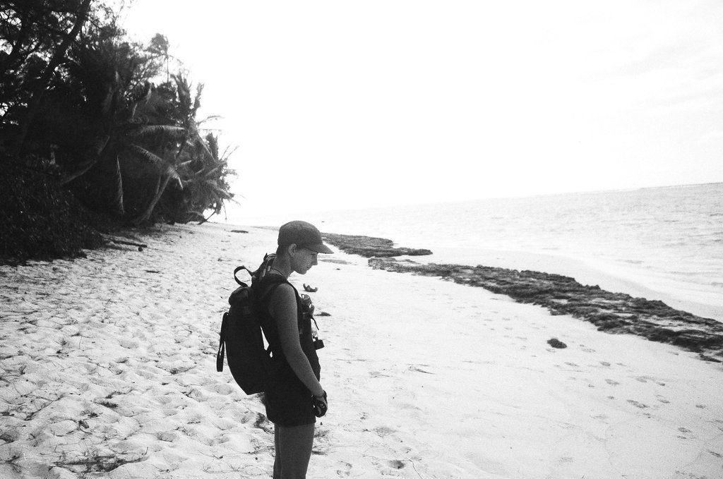 A photograph of Rek standing on the beach, appearing pensive