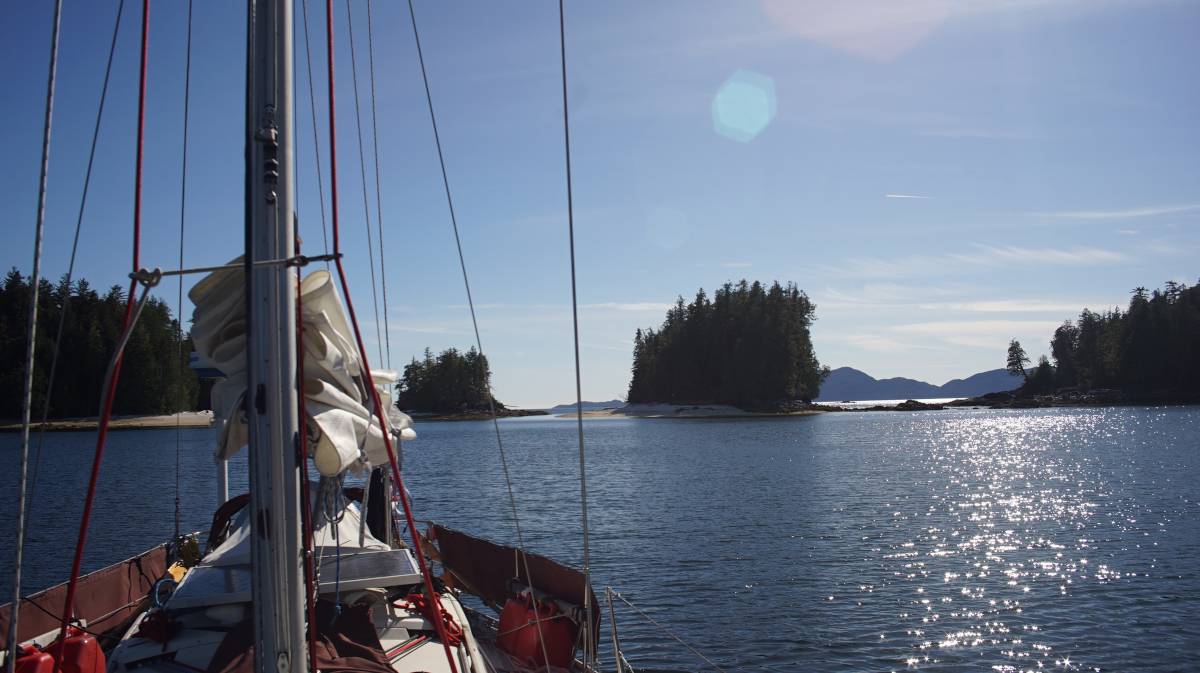 pino at anchor in fury cove with a white sand beach visible in the background on a bright spring day