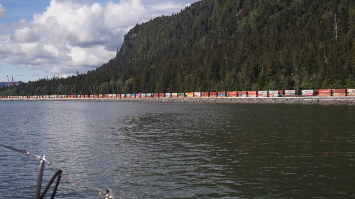 a very long line of colorful containers stacked onto a train
