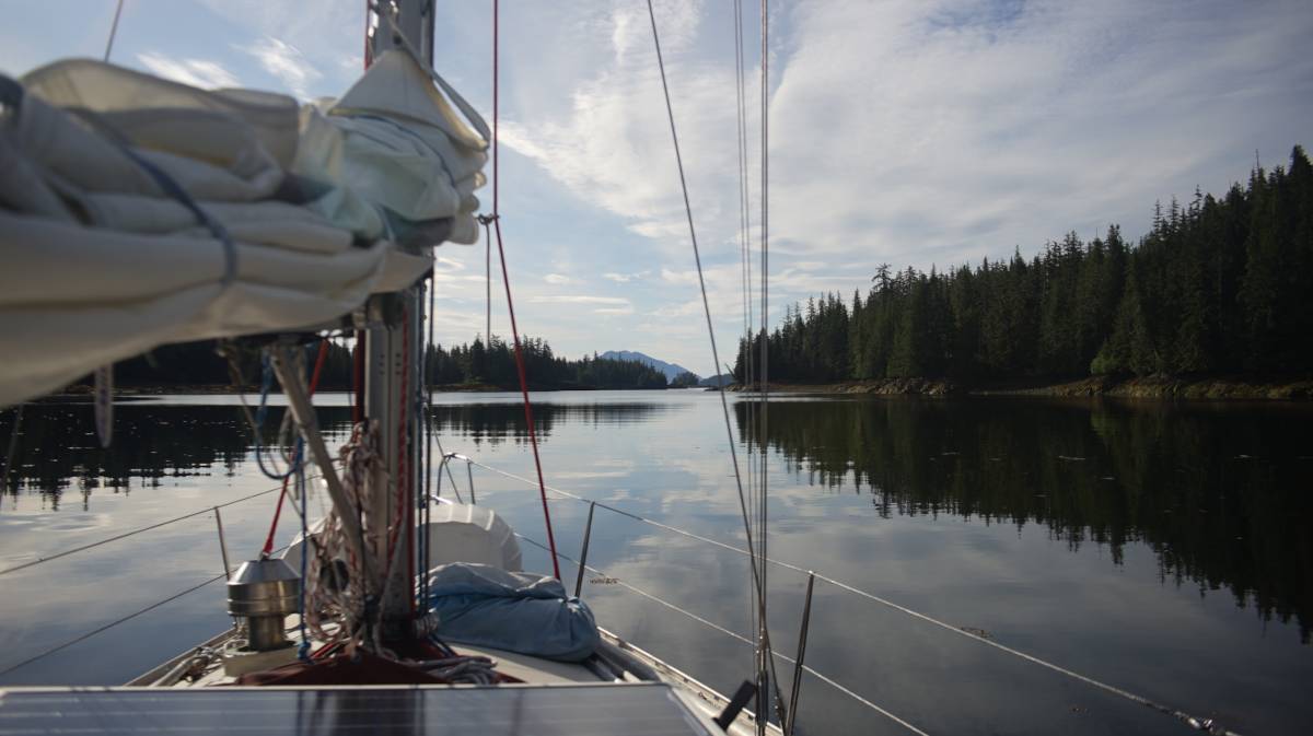 a view of the cove from the deck of a sailboat, a small islet is nearby