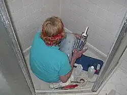 Repairing damaged tile in a shower stall with a caulking gun