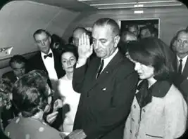 Johnson taking the oath of office aboard Air Force One, Jacqueline Kennedy to his left.