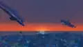 2 dolphins leaping above the ocean at sunset.