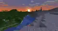 River running between forest and windswept hills biome with sunset in the background.