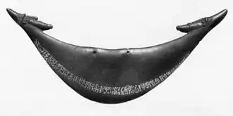 A crescent shaped piece of wood with two small heads at the tips. A line of small pictures runs the length of the crescent
