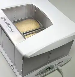 A box-shaped appliance with a window in the top that shows two loaves of bread inside