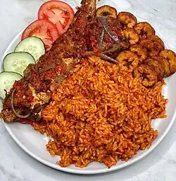Jollof rice served with fried fish and fried plantains