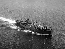 Aerial view of cargo ship at sea, with numerous large cranes and other loading equipment visible on the decks fore and aft