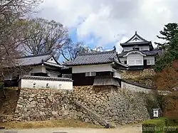 The castle consists of several white-walled and blue-roofed buildings on top of stone foundations