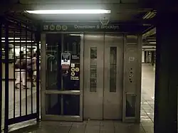 An elevator from the mezzanine to the southbound Broadway Line platform. It has a glass-and-metal enclosure and signage indicating that it leads to the "N", "Q", and "R" trains.
