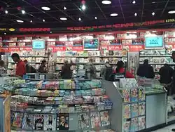 A newsstand showing many magazines. There are TVs showing the news in the background.
