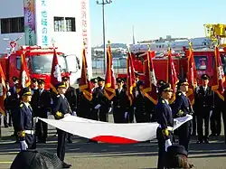 Firefighters in Tokyo holding the Japanese national flag during a ceremony