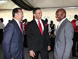 Three men wearing suits speaking with each other