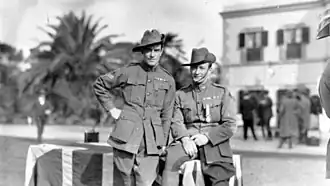 an outdoors photograph of two soldiers standing near a table