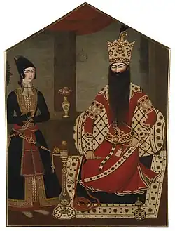 Portrait of two men, on the right a bearded monarch wearing a crown seated on a raised seat, on the left a young man standing, both wearing ornate royal robes