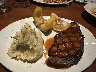 A plate including a roasted pork chop, smashed potatoes and acorn squash from J. Alexander's in Boca Raton, Florida
