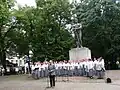The historian Eero Medijainen speaking on Estonian Independence Day in front of the Tartu War of Independence Monument, behind him the female choir Emajõe Laulikud&nbsp;[et], August 20, 2012