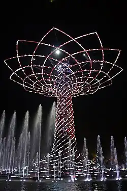 Large tree made of lights at night, surrounded by fountains