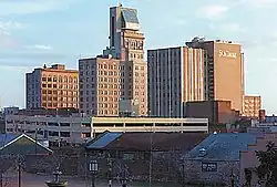The Lamar Building, a skyscraper with a pyramidal penthouse, as seen from a distance, with buildings on either side.