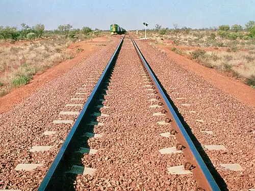 Photo of straight railway track with shiny rails and well-formed ballast laid level with the tops of the concrete sleepers or crossties