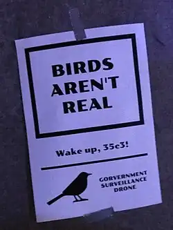 A poster from the movement, reading "Birds aren't real" with the subtitle "Wake up, 35c3!". At the footer, there is a silhouette of a small bird labelled as a "government surveillance drone".