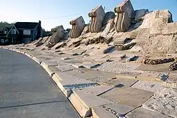Hay bales arranged in a triangular formation along the ground in a wide op[en prairie