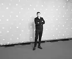a man standing in front of a backdrop with his arms crossed