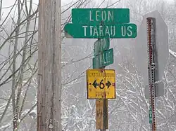 Example of a county route marker and fingerposts used by Cattaraugus County for its county routes prior to the late 1990s. The county now uses the standard pentagon; remaining older markers and fingerposts, including this New Albion example, have been left standing.