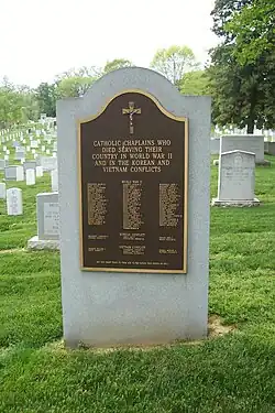 A tall stone monument stands on a grassy hill in a graveyard