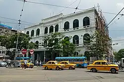 Three-story building, viewed from the street with trees in the foreground