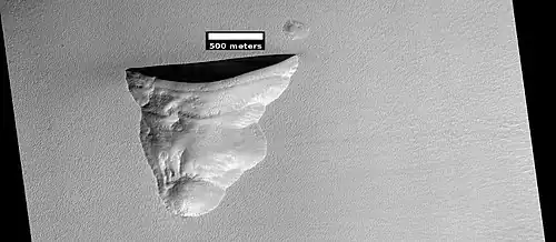 Wide view of triangular depression, as seen by HiRISE. The wall which faces the south pole contains ice in distinct layers that are visible in next image. Location is Hellas quadrangle.[97]