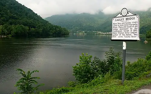 scenic river view with mountains covered with trees and historical marker