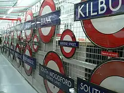 A collection of London Underground roundels from many stations displayed on a wire mesh screen