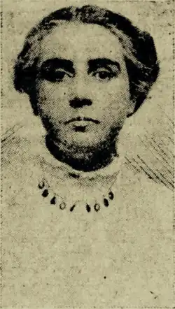 B&W portrait photo of a woman with her hair in an up-do, wearing a pale blouse and necklace.