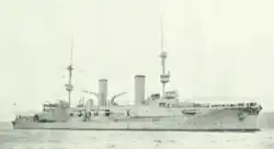 A large, light gray ship with two tall masts and two smoke stacks