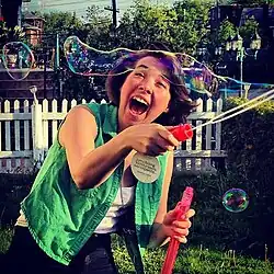A woman creating bubbles with a long soap bubble wand