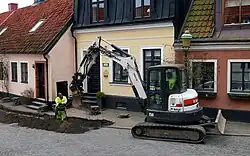 A smaller excavator is digging for the laying of a broadband cable in central Ystad in 2021