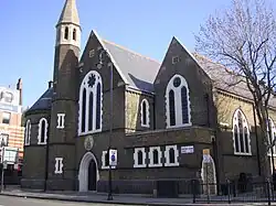 The former St Barnabas Church, Kentish Town Road, Camden in London, 1884–85 by Ewan Christian, now the Greek Orthodox Cathedral of St Andrew, showing the west front with north apse and turret[162]