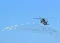 An SH-60B deploys its flares while evasively maneuvering