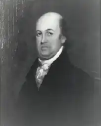 A bald man in a white shirt and tie and black jacket
