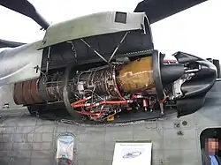 side view of a helicopter with the engine bay open, displaying engine internals