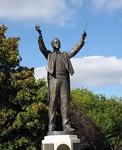 outdoor full length statue showing Holst conducting