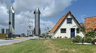Two large spacecraft next to a v-shaped roof house
